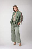 Model wearing a sage green jacket with colourful embroidered sleeve panels